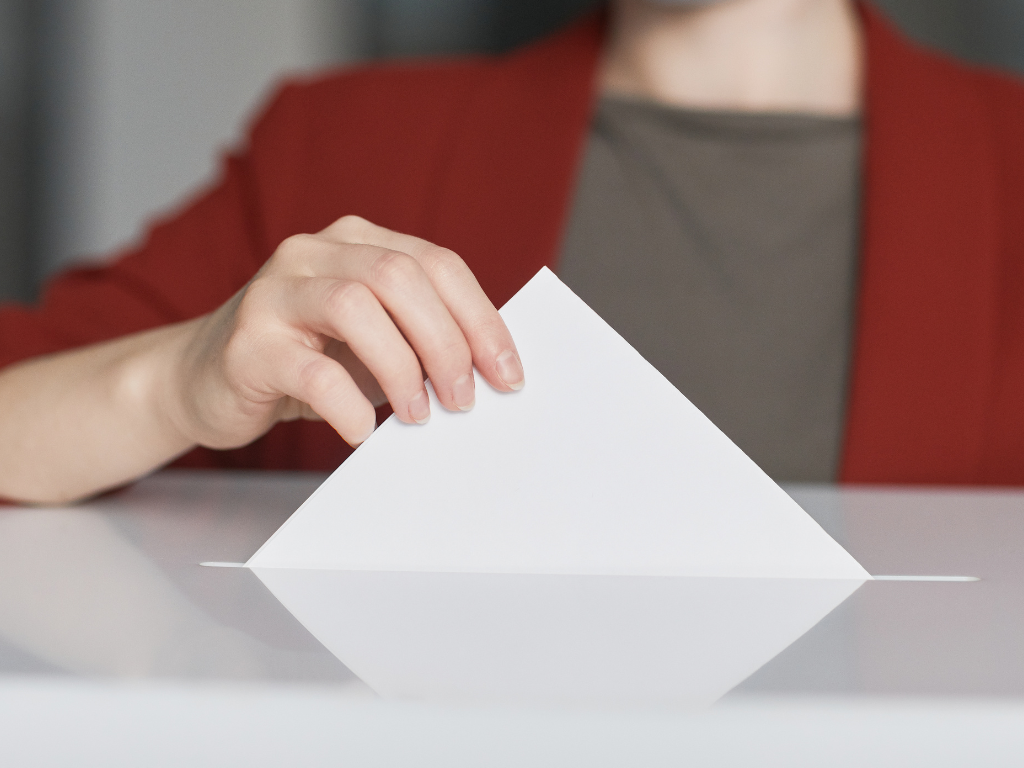  Una mà introduint un vot en una urna.